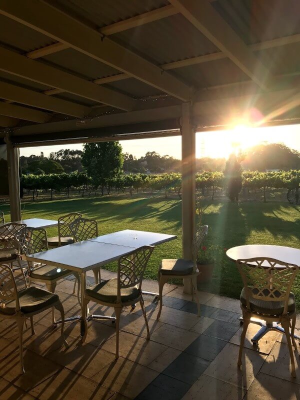 table-and-chairs-on-a-verandah-at-pinelli-estate-winery-restaurant-looking-at-the-sunset
