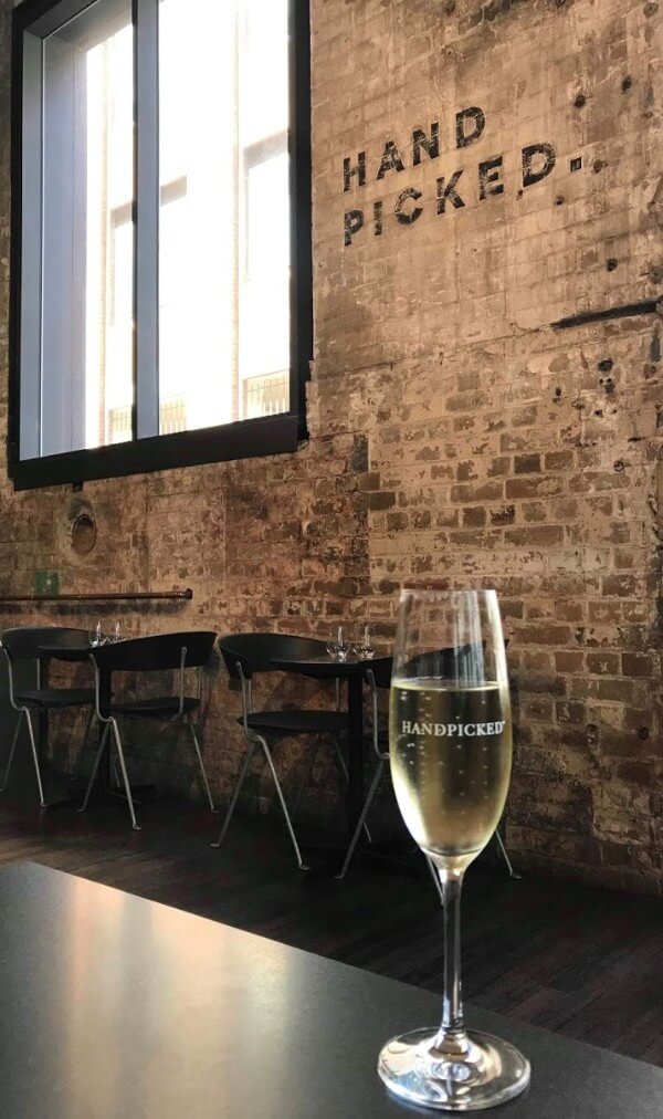 glass of sparkling wine on table against brick wall